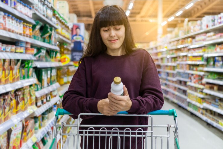 Una mujer leyendo una etiqueta de producto con carros en el supermercado. Concepto de compras