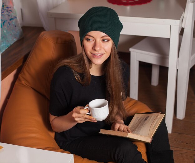 Mujer leyendo un libro y bebiendo té en la cafetería