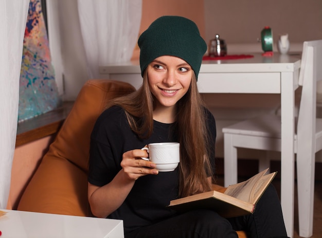 Mujer leyendo un libro y bebiendo té en la cafetería