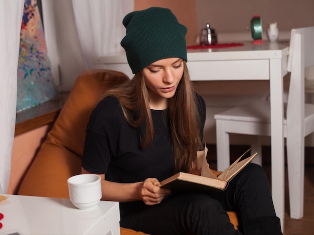 Mujer leyendo un libro y bebiendo té en la cafetería