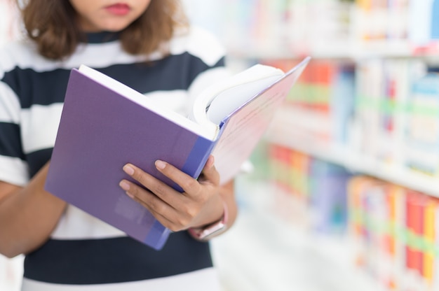 Mujer leyendo un libro en la biblioteca, enfoque selectivo