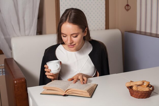 Mujer leyendo un libro en la cafetería y bebiendo té