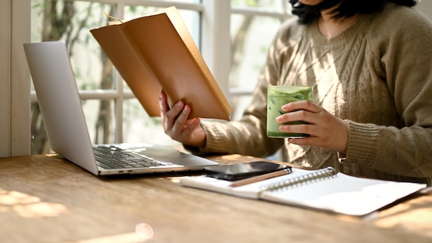 Una mujer leyendo un libro mientras disfruta de su té verde matcha helado en una cafetería