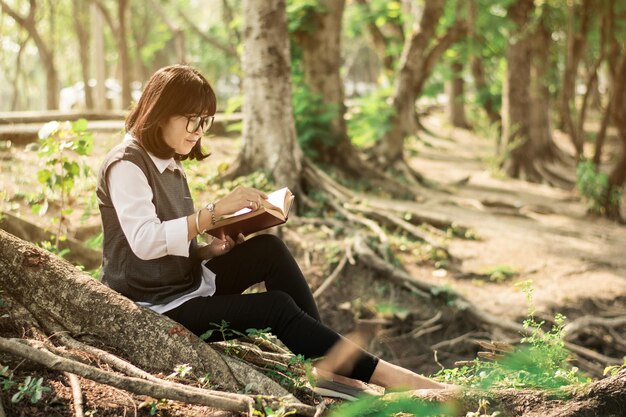 Mujer leyendo un libro mientras está sentada en el bosque