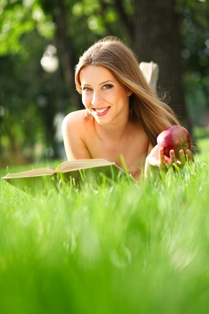 Mujer leyendo un libro en el parque sobre el césped