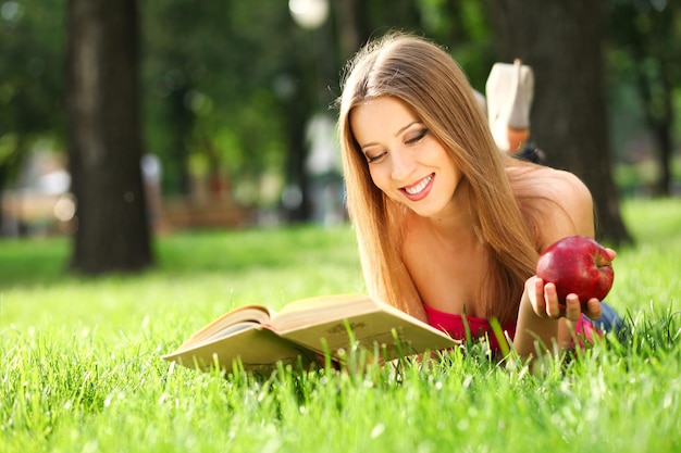 Mujer leyendo un libro en el parque sobre el césped