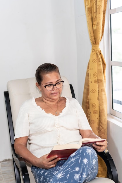 Mujer leyendo un libro sentada en el salón de su casa