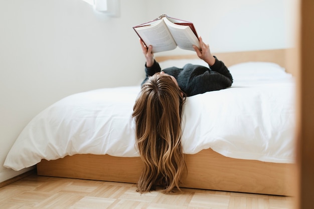 Mujer leyendo un libro en su cama durante la cuarentena por coronavirus