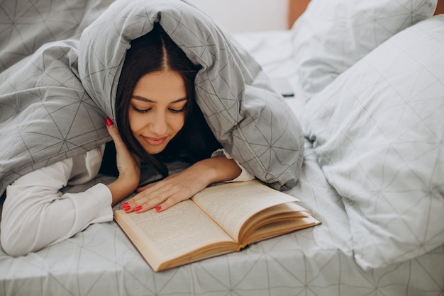 Mujer leyendo un libro en su cama