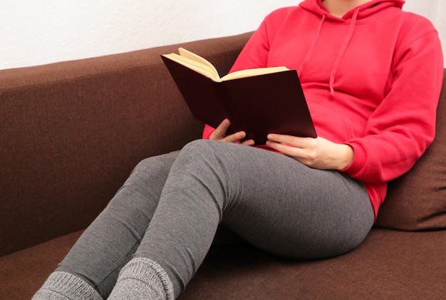 Mujer leyendo un libro y tumbada en el sofá. Vista superior