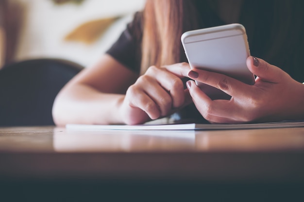 Mujer leyendo un libro y usando un teléfono inteligente