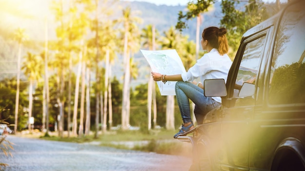 Foto mujer leyendo un mapa blanco sentada en un coche en el bosque