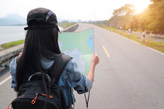 Mujer leyendo un mapa mientras está de pie en la carretera