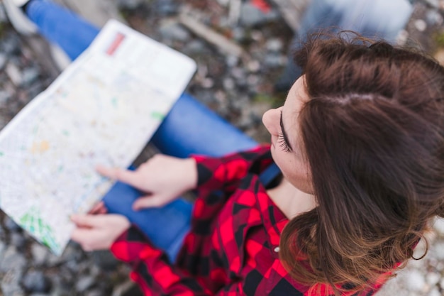 Foto mujer leyendo un mapa mientras está sentada al aire libre