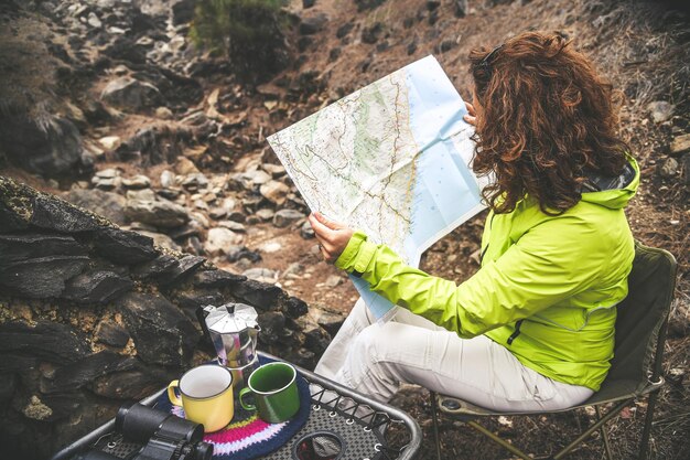 Foto mujer leyendo un mapa mientras está sentada en una silla en el bosque