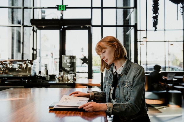 Mujer leyendo un periódico en un café