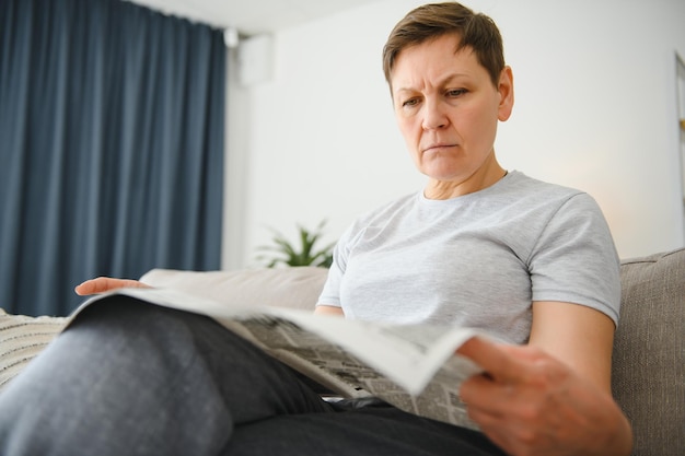 Mujer leyendo el periódico en casa