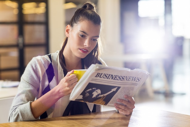 Foto mujer leyendo el periódico en la oficina