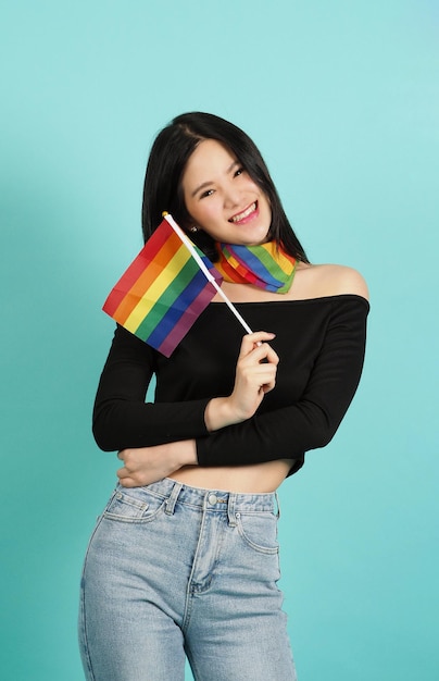 Mujer LGBTQ sosteniendo la bandera del orgullo contra un fondo verde azul