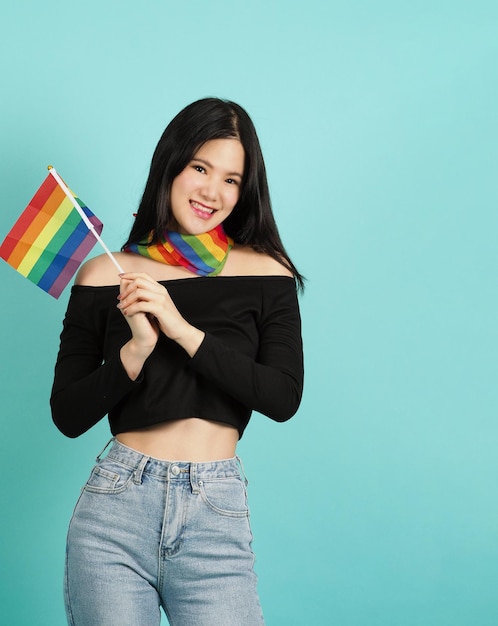 Mujer LGBTQ sosteniendo la bandera del orgullo contra un fondo verde azul