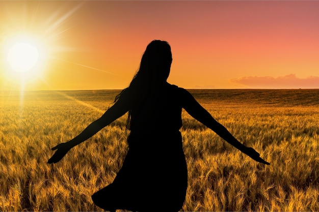 Mujer de la libertad feliz y libre con los brazos abiertos en la playa al atardecer soleado.