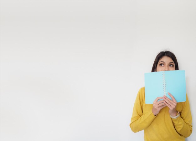 Foto mujer con un libro de pie contra la pared