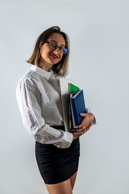 Mujer con libros en las manos posando con ropa elegante en un fondo blanco aislado