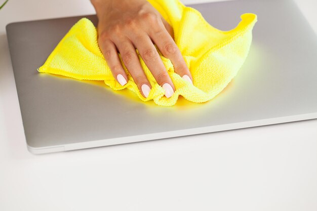 La mujer limpia la computadora portátil con una toallita desinfectante húmeda