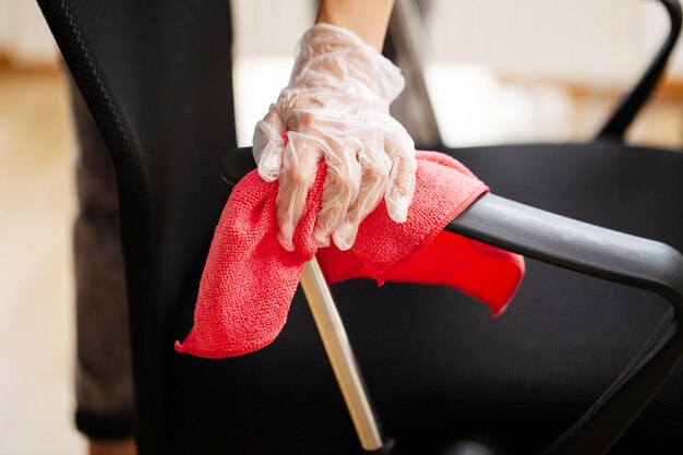 Mujer limpia muebles en la oficina con una toallita desinfectante húmeda