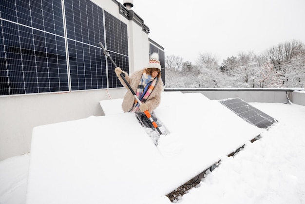 Mujer limpia paneles solares de la nieve