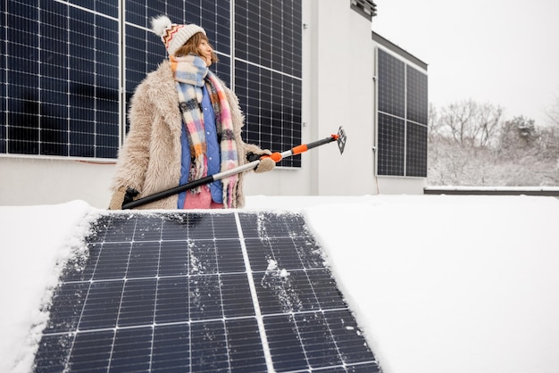 Mujer limpia paneles solares de la nieve