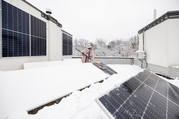 Mujer limpia paneles solares de la nieve