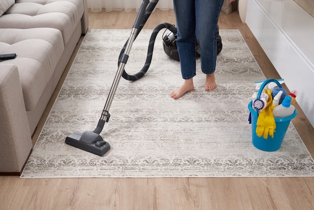 Mujer limpiando la alfombra con aspiradora en el salón