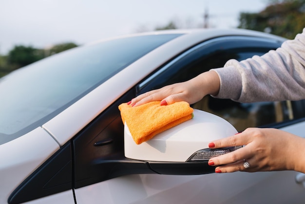 Una mujer limpiando el automóvil con un paño de microfibra, el concepto de detalles del automóvil (o valet)