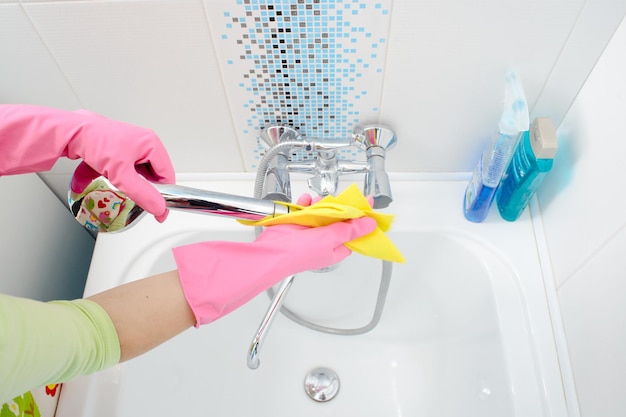 Una mujer limpiando el baño en casa Mujer lavando la bañera y el grifo