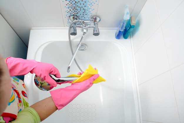 Una mujer limpiando el baño en casa Mujer lavando la bañera y el grifo