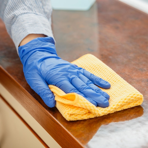 Mujer limpiando la encimera de la mesa en la cocina con un paño húmedo