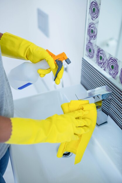 Mujer limpiando el lavamanos en el baño