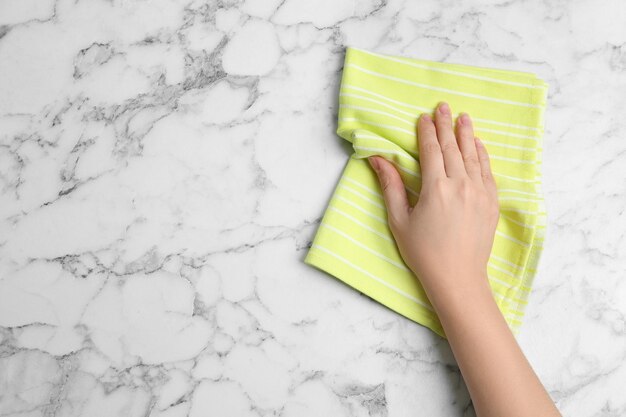 Mujer limpiando mesa de mármol blanco con toalla de cocina vista superior Espacio para texto
