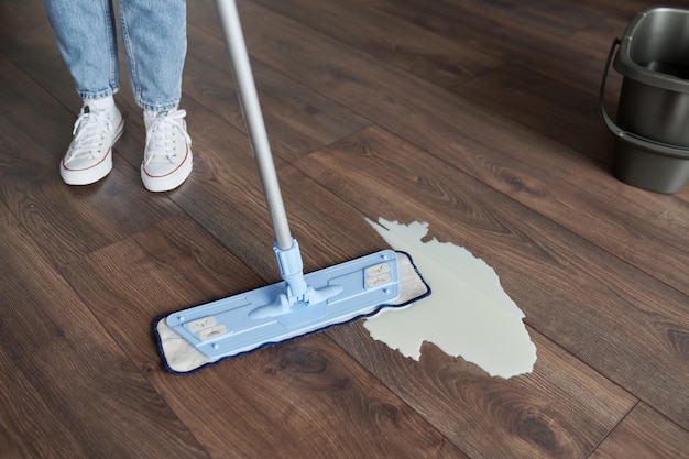 Mujer limpiando el piso sucio con un trapeador