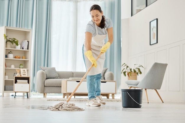 Mujer limpiando el piso con un trapeador en la sala de estar en casa con una sonrisa Limpiador asiático feliz haciendo tareas domésticas o trabajo en una habitación de hotel o casa limpia mientras sonríe y solo limpia primavera