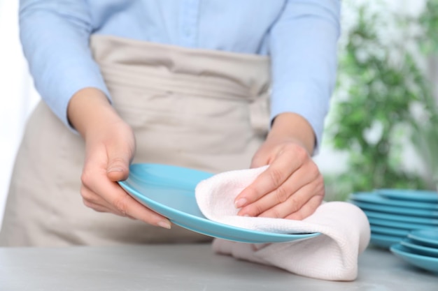 Mujer limpiando el plato limpio en el primer plano de la mesa