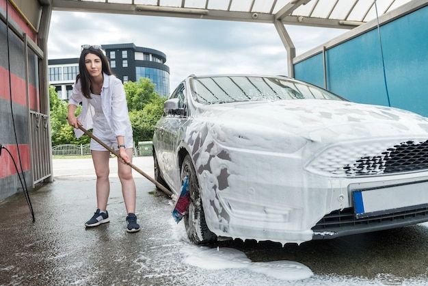 Mujer limpiando la rueda del coche con cepillo y espuma. Concepto de limpieza