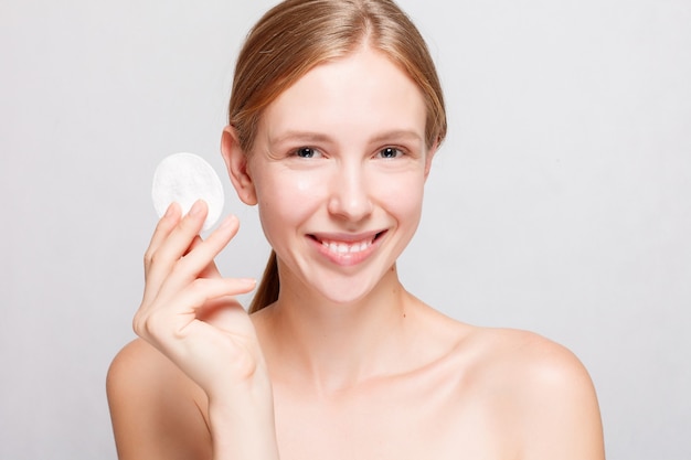 Mujer limpiando su rostro con un algodón