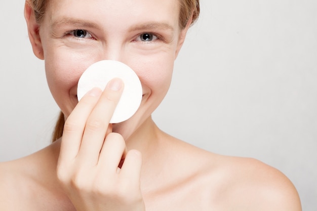 Mujer limpiando su rostro con algodones