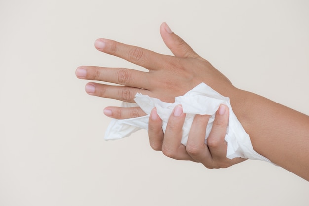 Mujer limpiando sus manos con un pañuelo de papel. Cuidado de la salud y concepto médico.