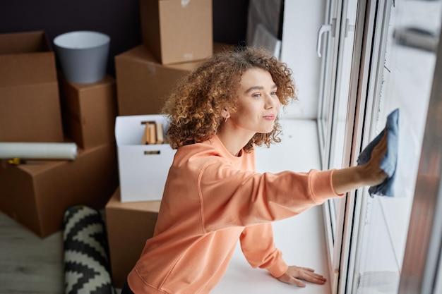 Mujer limpiando ventanas en apartamento nuevo