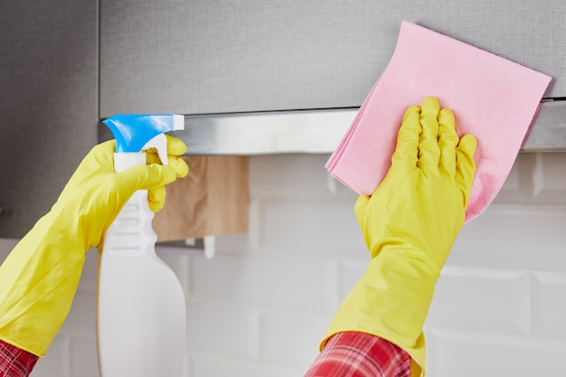 Mujer de limpieza de cocina. Mujer joven lavar la campana de la cocina con spray. De cerca