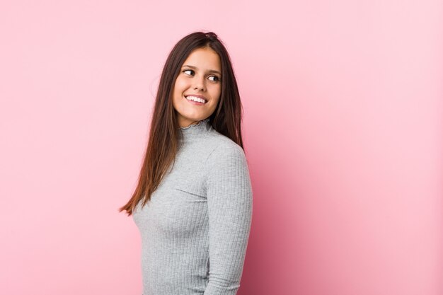 La mujer linda joven mira a un lado sonriente, alegre y agradable.