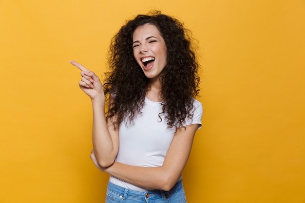 Mujer linda joven posando aislada en amarillo apuntando.